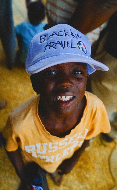 A child in a Black Kids Travel hat